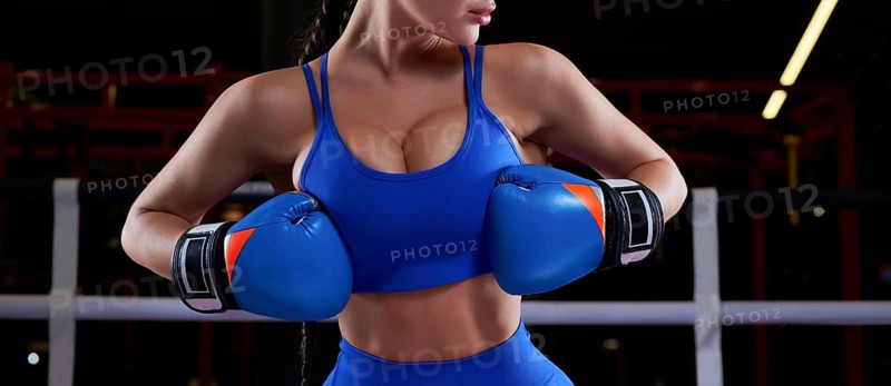 Woman boxer in blue gloves in the ring. Sports concept