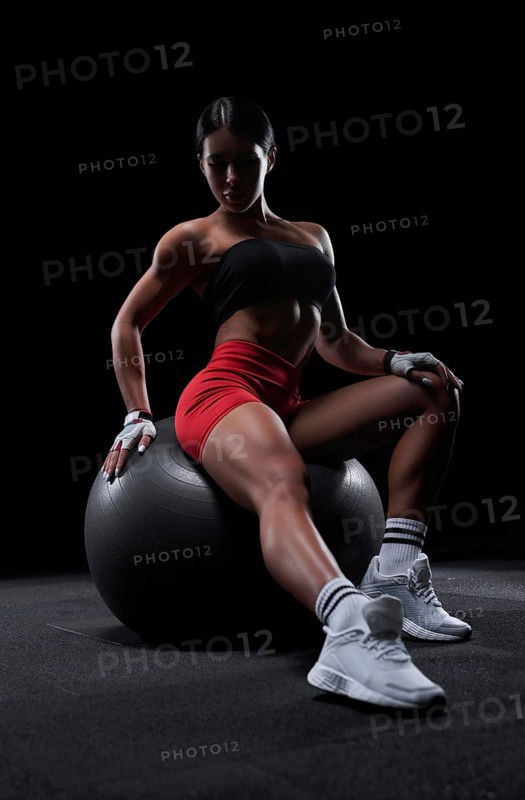 Athletic girl working out in gym. Fitness woman training with pilates ball. Mixed media