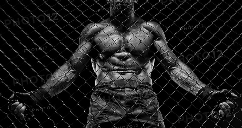 Black and white image of a man in a boxing cage. The concept of sports
