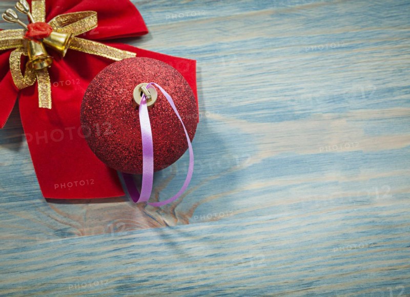 Red Christmas ball bow with bell on wooden board holidays concept