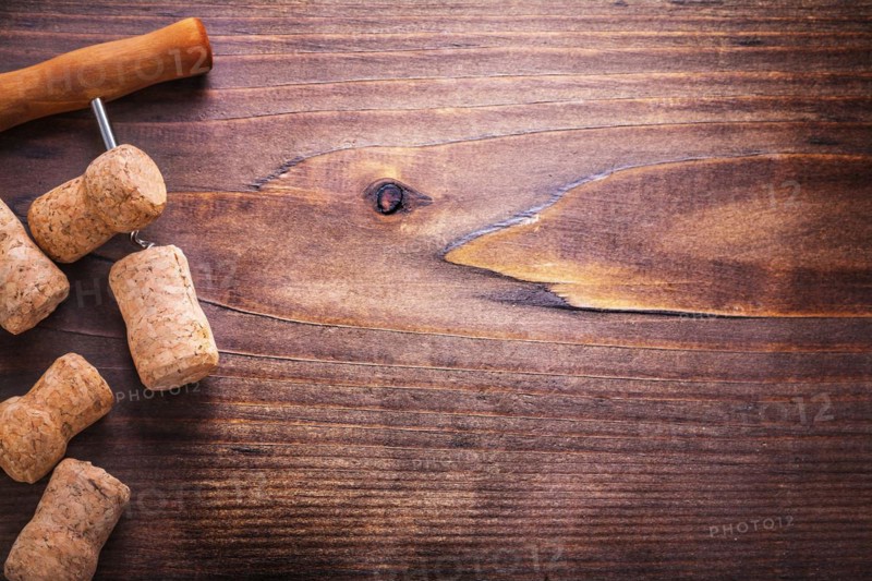 Champagne corks and corkscrew on vintage wooden board with copyspace alcohol concept