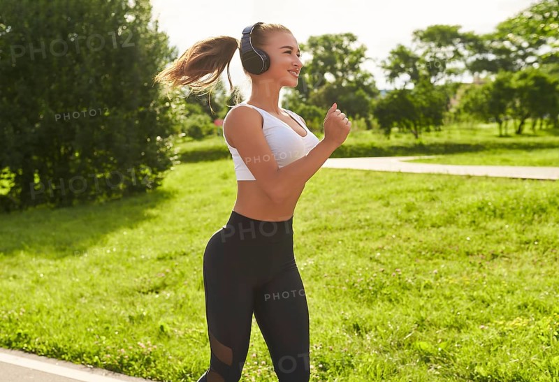 Fitness girl in sportswear runs through the evening sunny park. Healthy lifestyle. Mixed media