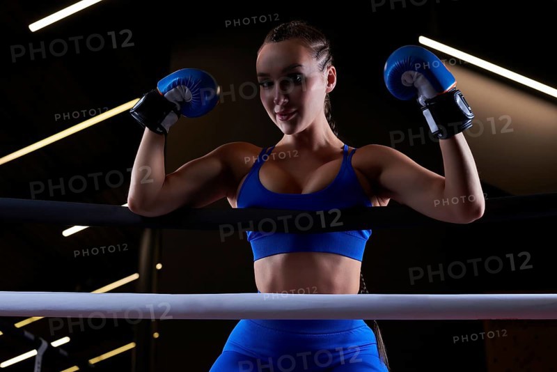 Beautiful and strong sportswoman posing on the ropes of the ring. The concept of wrestling and boxing. Mixed media