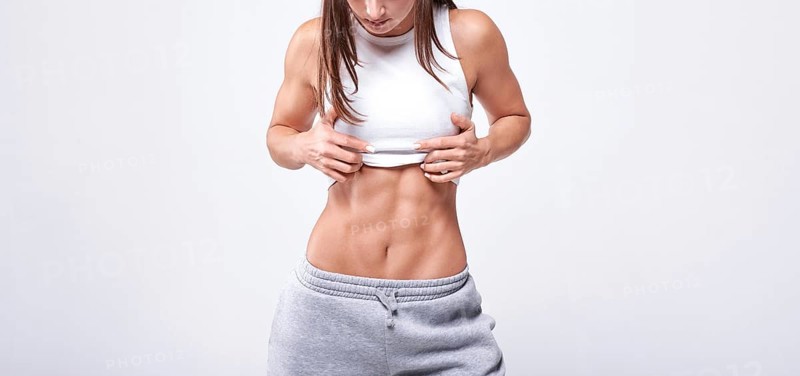 No name portrait. Young white fitness woman wearing sportswear standing over white wall background. Fitness concept. Mixed media