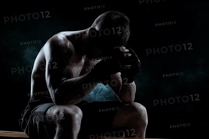Kickboxer with overlays on his hands prays before the fight. The concept of mixed martial arts. MMA