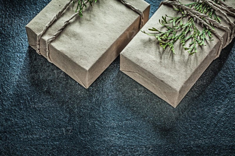 Handmade present boxes with thuya branch on black background top view holidays concept