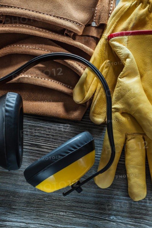 Leather safety gloves tool belt earmuffs on wooden board