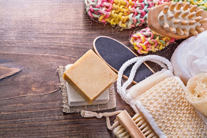 Large set of bathroom accessories bar soap wisp massager loofah nail brush on vintage wooden board with small copyspace