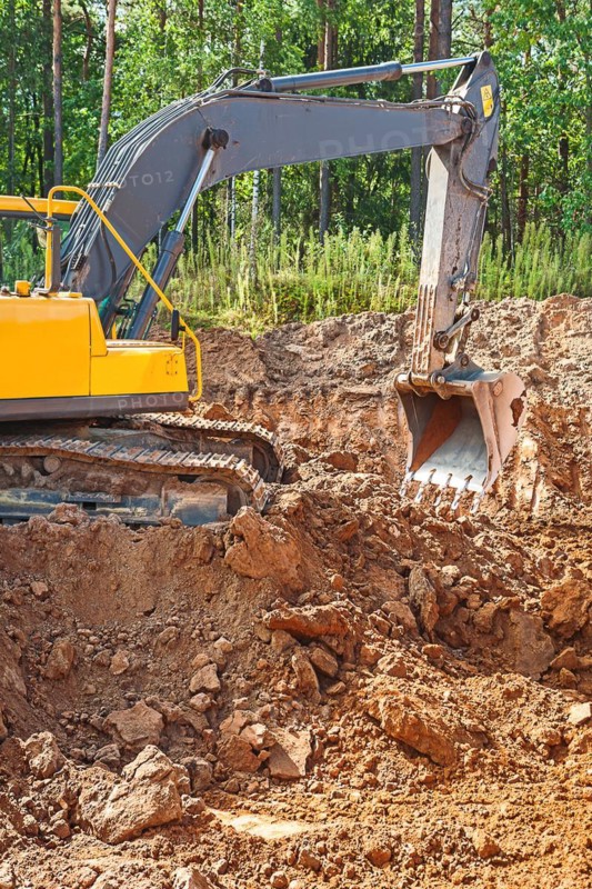 Excavator excavating clay soil on a construction site in the forest