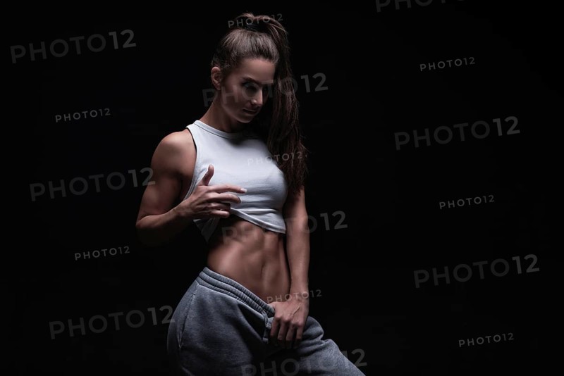 Athletic fitness woman posing in the studio on a dark background. Photo of an attractive woman in fashionable sportswear. Sports and healthy lifestyle. Mixed media