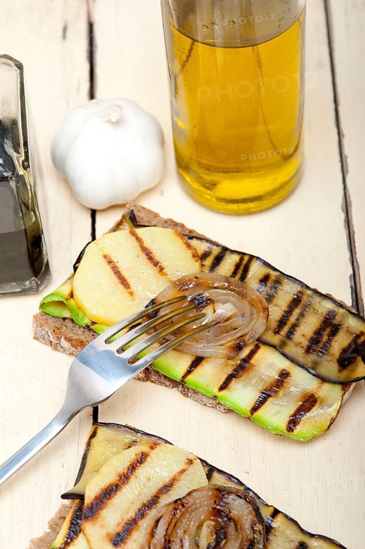 Grilled vegetables on rustic bread over wood table