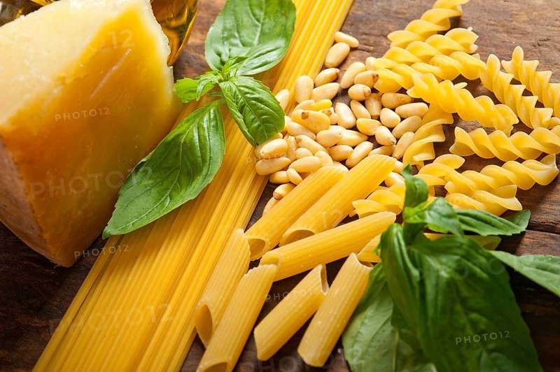 Italian basil pesto ingredients and raw pasta over old wood macro