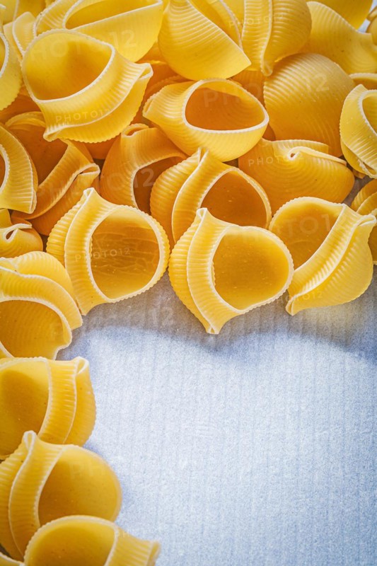 Heap of raw shell macaroni on blue background food and drink concept