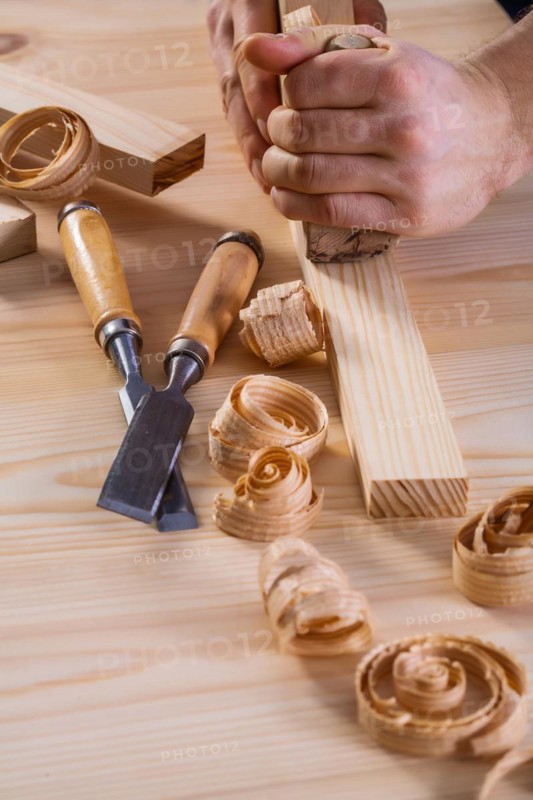 Close-up of a carpenter's hands with a plane and chisel