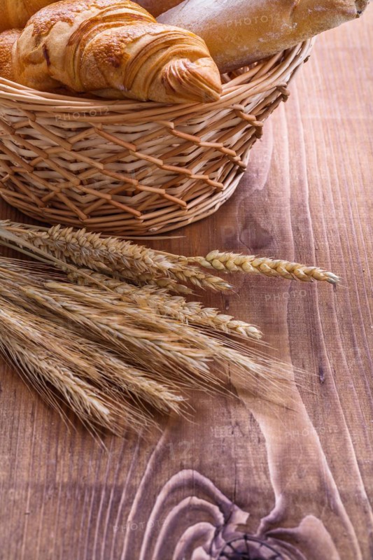 Croisants in a wicker basket and ears on an old wooden board