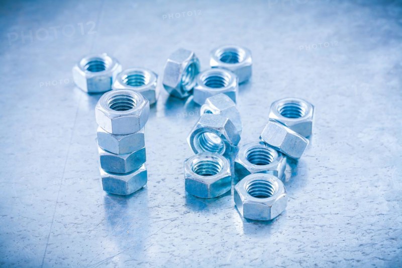 Metal threaded nuts on a metallic background Construction concept