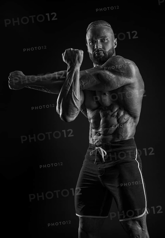 Silhouette of a strong bodybuilder. Confident young fitness athlete with a powerful body and perfect abs. Black and white photography. Dramatic light. Mixed media