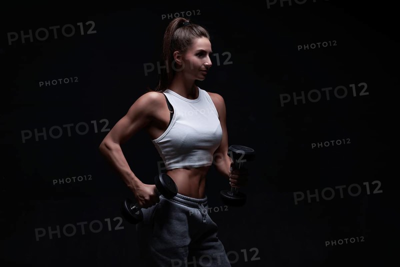 Athletic fitness woman posing in the studio on a dark background. Photo of an attractive woman in fashionable sportswear. Sports and healthy lifestyle. Mixed media