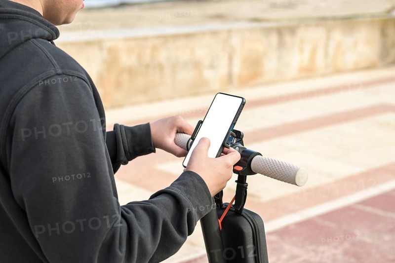 Top side view 14-20 years old riding scooter using mobile phone navigation route outdoors in nature