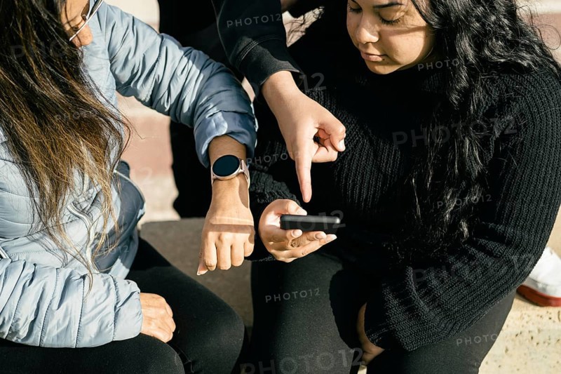 Happy friends sharing multimedia content online with their smartphones and smartwatch