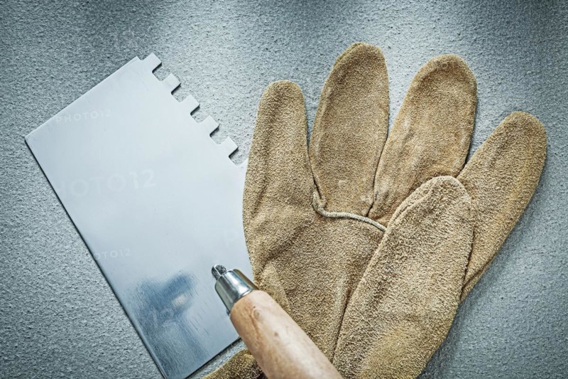 Bricklaying trowel working gloves on concrete background construction concept