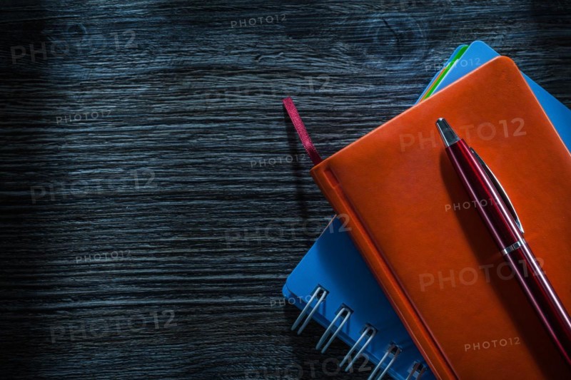 Composition of pocketbooks pen on vintage wooden board