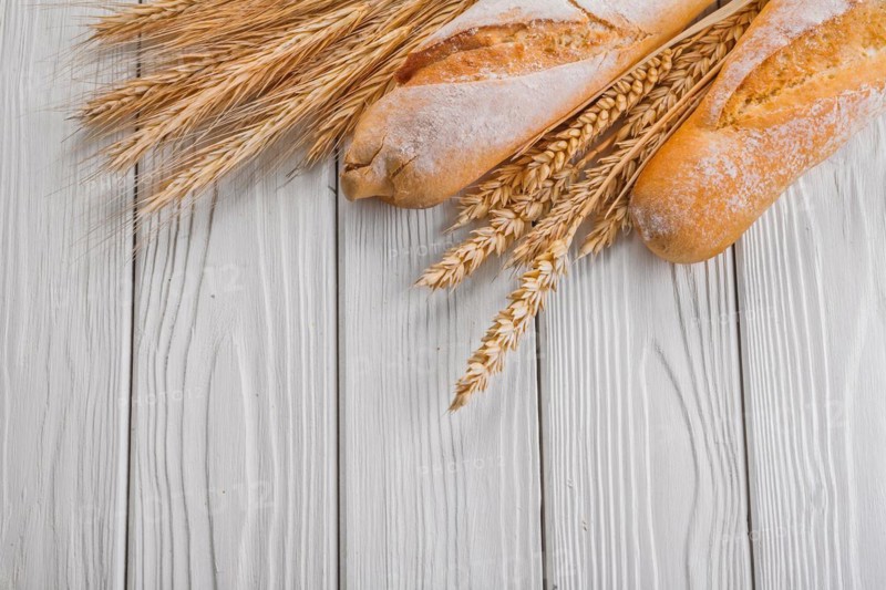 Baguettes and ears of wheat rye on vintage wooden painted boards food and drink concept