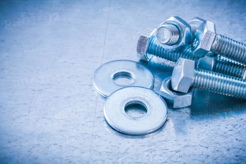 Metal threaded bolts nuts and bolts washers on metallic background copy space image construction concept