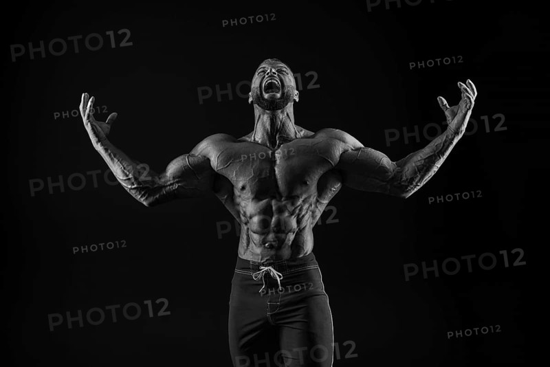 Silhouette of a strong bodybuilder. Confident young fitness athlete with a powerful body and perfect abs. Black and white photography. Dramatic light. Mixed media