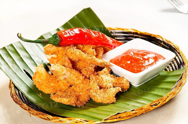 Fresh deep fried buffalo shrimps with a red chili pepper on top and sweet and sour sauce dip on side