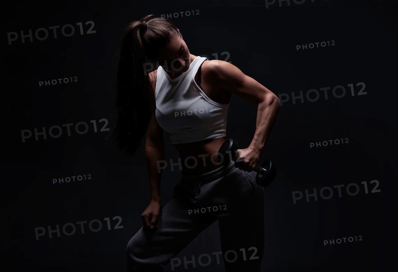 Athletic fitness woman posing in the studio on a dark background. Photo of an attractive woman in fashionable sportswear. Sports and healthy lifestyle. Mixed media