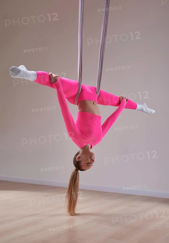 Image of a beautiful woman posing in a bright studio near the hammocks. The concept of airstretching. Fitness and sports