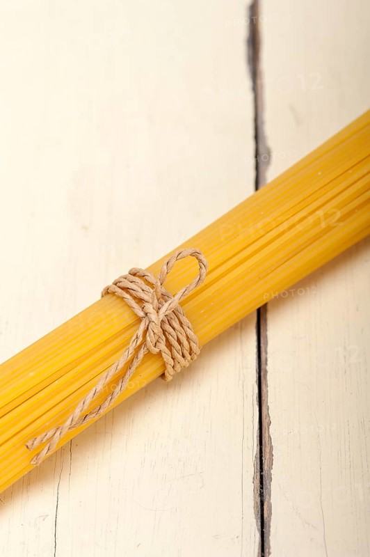 Italian pasta spaghetti tied with a rope on a rustic table