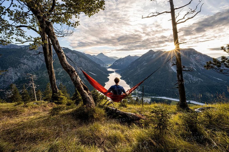 Young man sitting in an orange hammock