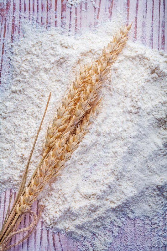 Ears of rye on white natural flour and vintage wooden boards Food and drink concept