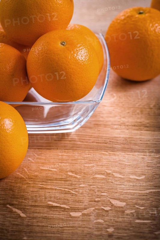Orange fruit in a square glass bowl on a wooden table