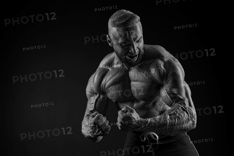 Silhouette of a strong bodybuilder. Confident young fitness athlete with a powerful body and perfect abs. Black and white photography. Dramatic light. Mixed media