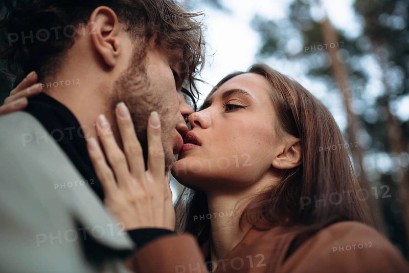 Romantic couple of lovers kisses on a date in the park in cold weather. Fashionable couple in coat