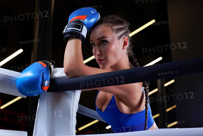 Beautiful and strong sportswoman posing in the corner of the ring. The concept of wrestling and boxing. Mixed media