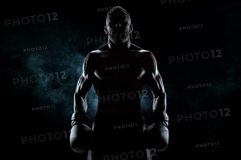 Kickboxer in black gloves posing on a background of smoke. The concept of mixed martial arts. MMA