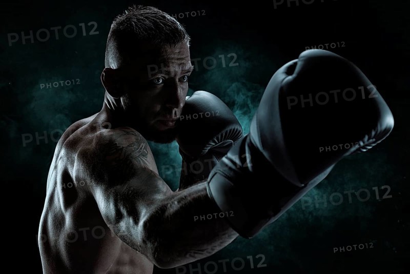 Kickboxer in black gloves posing on a background of smoke. The concept of mixed martial arts. MMA
