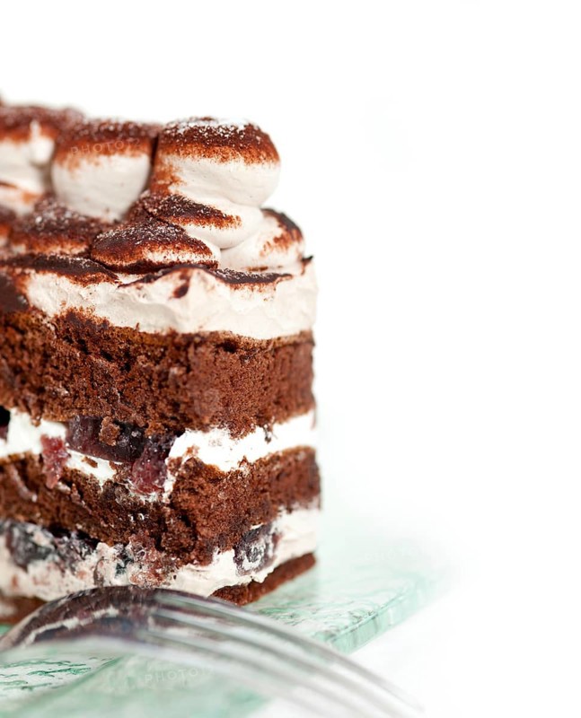 Fresh whipped cream dessert cake slice with cocoa powder on top