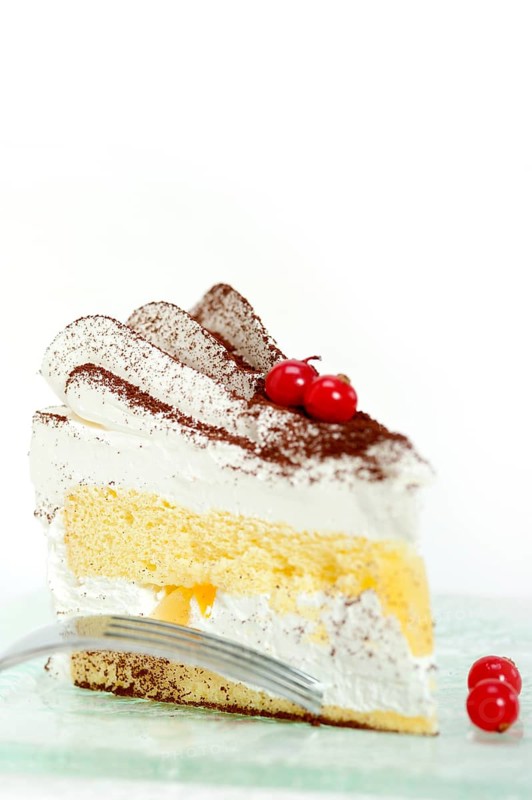 Fresh ribes and whipped cream dessert cake slice with cocoa powder on top