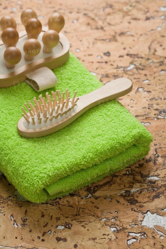Massager and hairbrush on a green towel