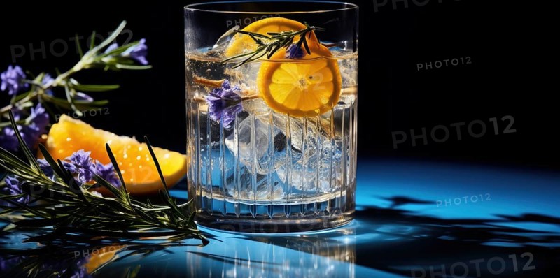 A glass of a cold beverage with ice cubes and lemon slices