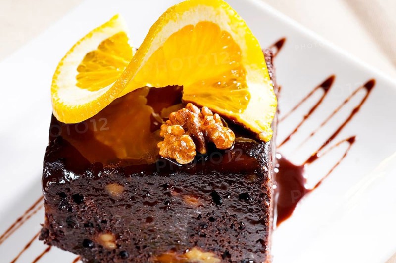 Fresh baked delicious chocolate and walnuts cake with slice of orance on top