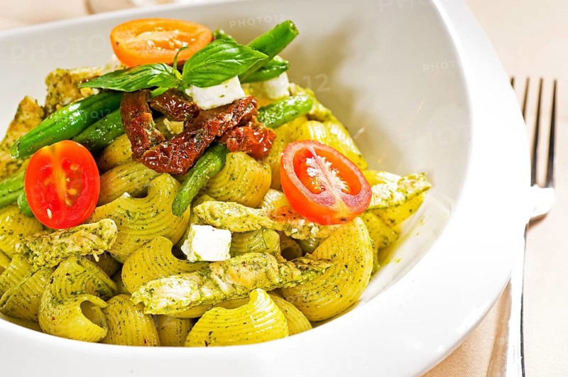Fresh lumaconi pasta and pesto sauce with vegetables and sundried tomatoes