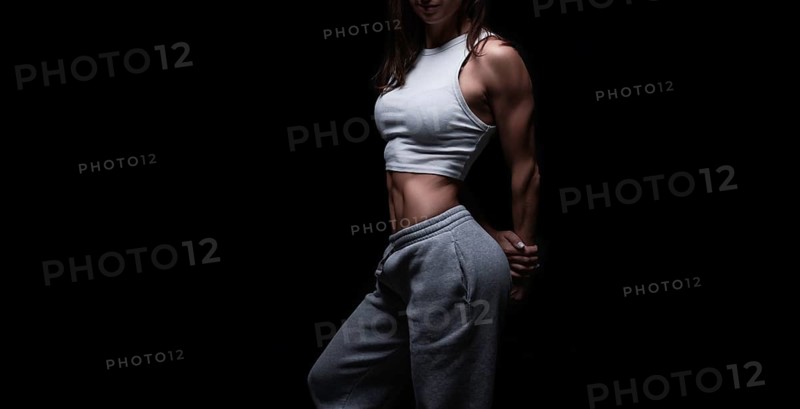 Athletic fitness woman posing in the studio on a dark background. Photo of an attractive woman in fashionable sportswear. Sports and healthy lifestyle. Mixed media