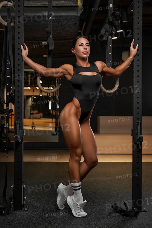Sexy fitness woman. A beautiful athletic girl in a black bodysuit poses in the gym. Sports and fitness concept