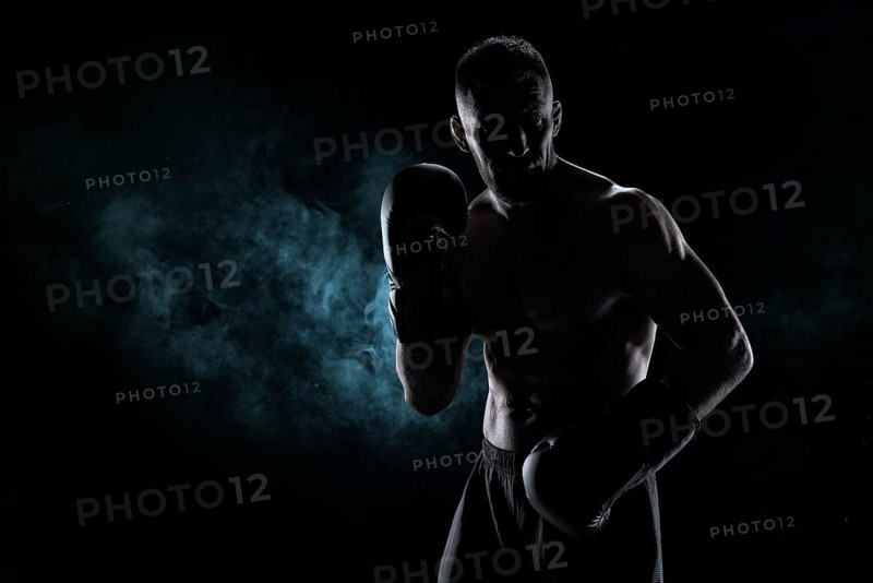 Kickboxer in black gloves posing on a background of smoke. The concept of mixed martial arts. MMA